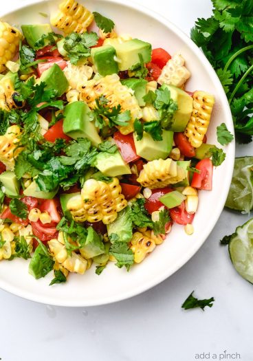 Grilled corn salad features fresh summer corn with avocado, tomato, jalapeno, and onion. A delicious, quick, easy and healthy recipe that is perfect for summer barbecues! // addapinch.com