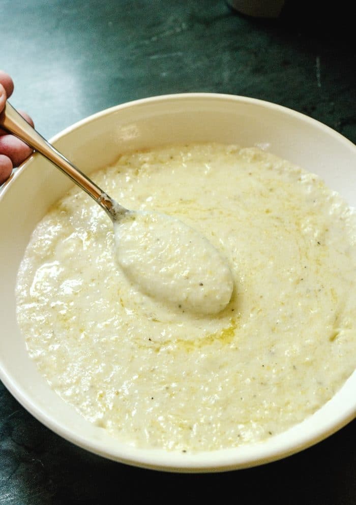 Spoon with buttery bite of Instant Pot Grits served in a white bowl // addapinch.com