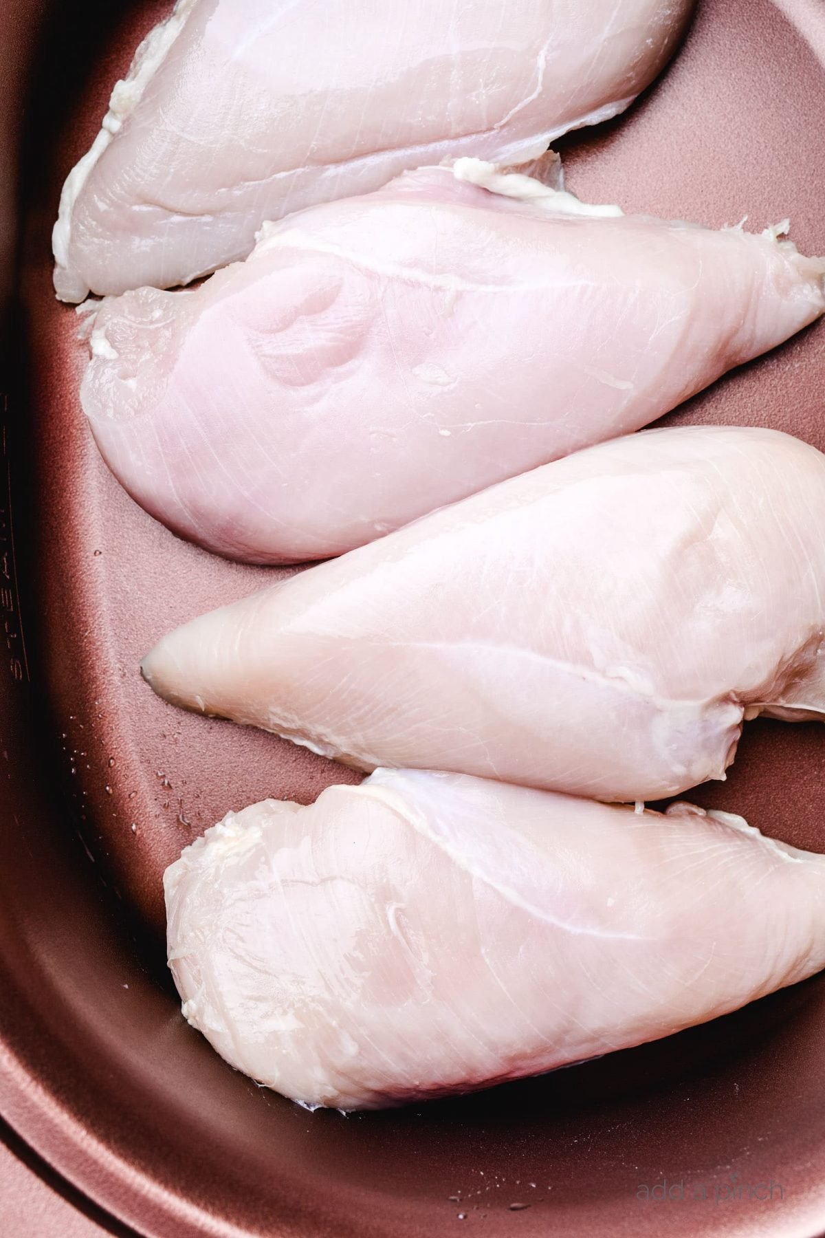 Boneless skinless chicken breasts in a slow cooker.