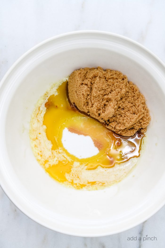 White mixing bowl with brown and granulated sugars, melted butter and vanilla // addapinch.com