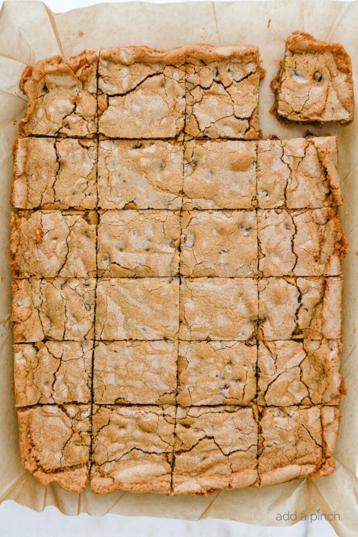 Baked Pecan Chewies cut into squares on brown parchment // addapinch.com