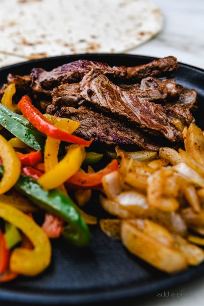 Ribeye Fajitas with peppers, onions, and served with tortillas, guacamole, and restaurant style salsa. // addapinch.com