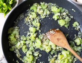 Garlic, onions, celery, parsley and rosemary sauteing in a skillet.