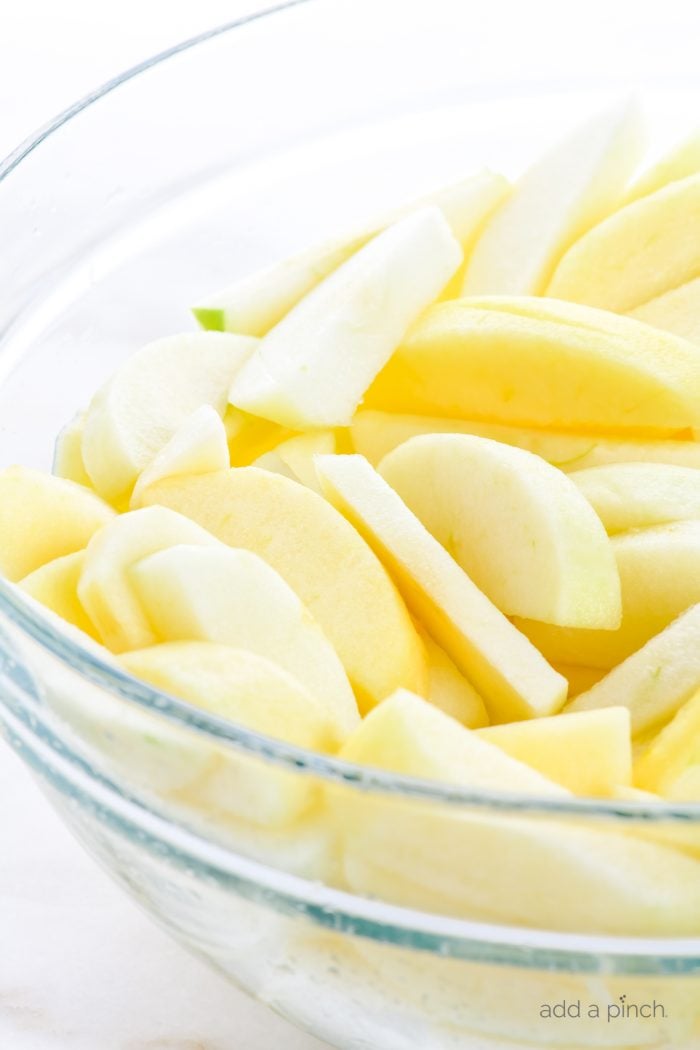 Glass bowl with peeled and sliced apples. 
