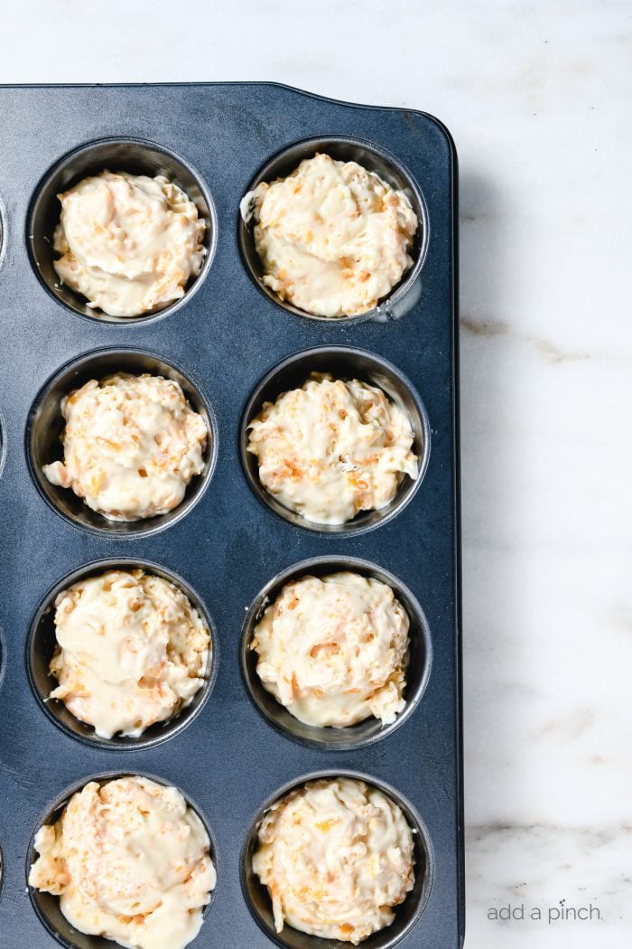 Muffin tin with cheesy muffin dough.