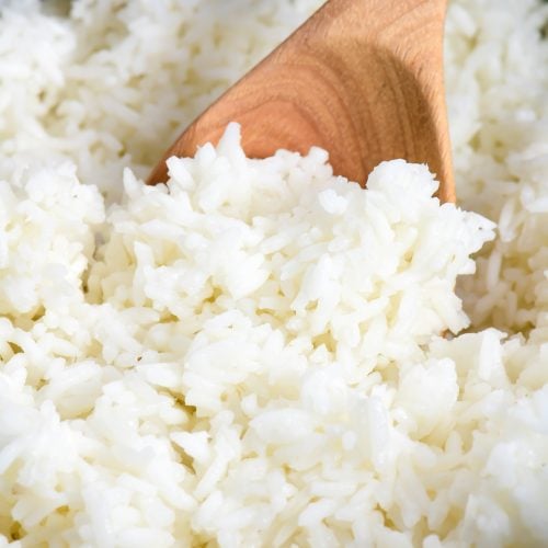 Fluffy white rice in a white Dutch oven with a wooden spoon. // addapinch.com