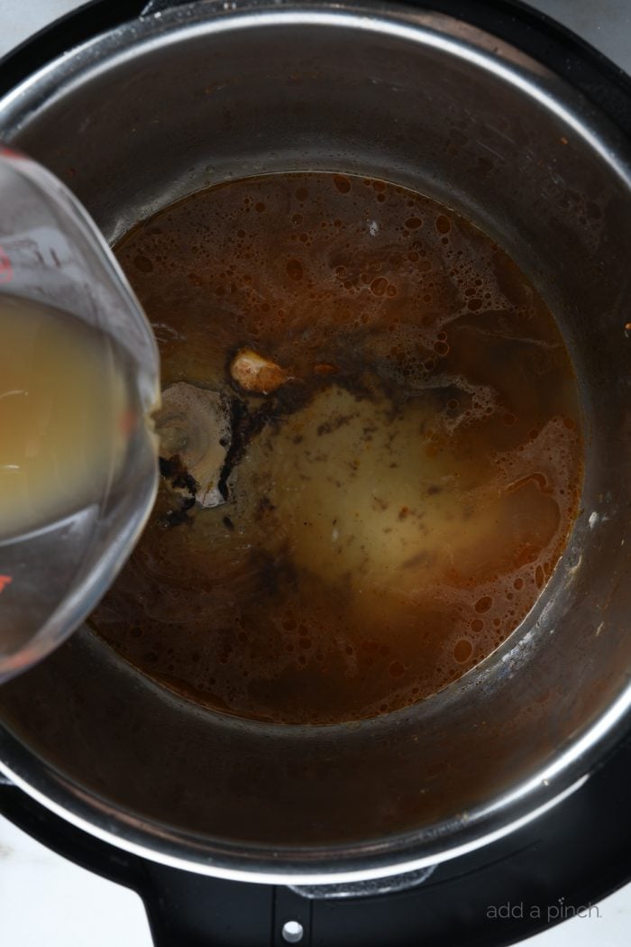 Chicken stock being added to Instant Pot to cook whole chicken. // addapinch.com