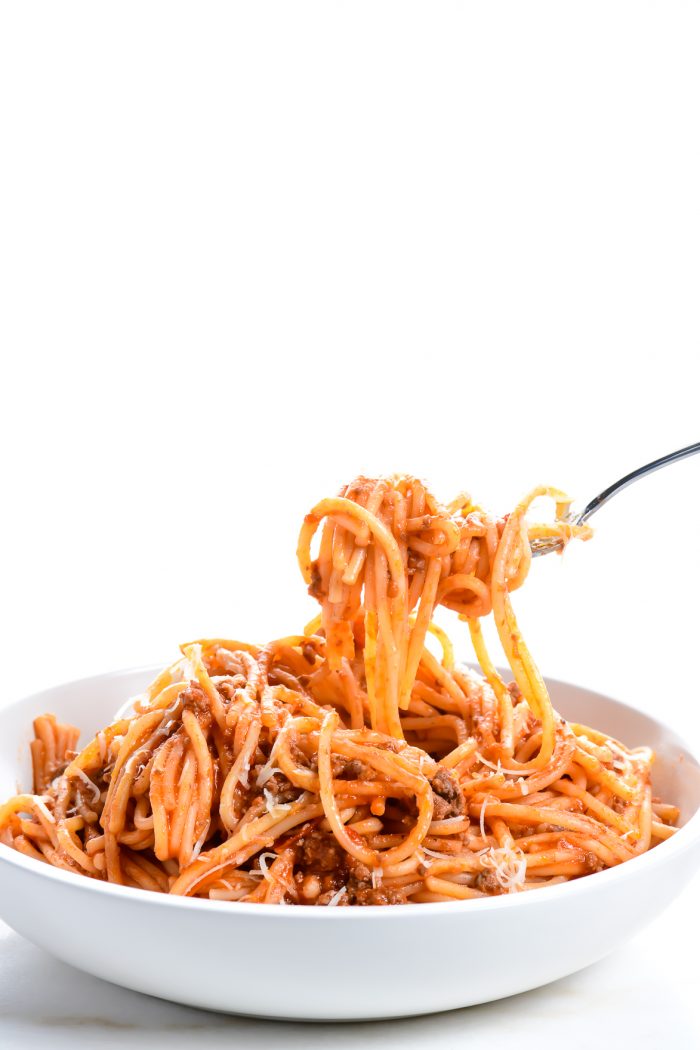 White bowl and fork twirling spaghetti with meat sauce // addapinch.com