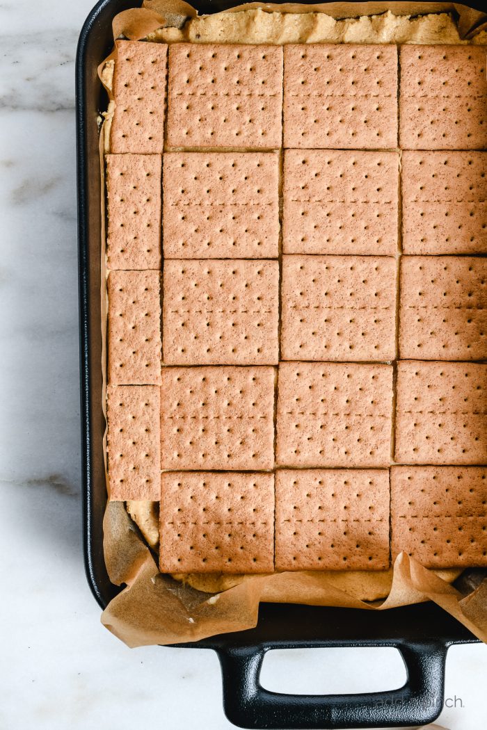 Black baking dish lined with parchment, layered with graham crackers // addapinch.com