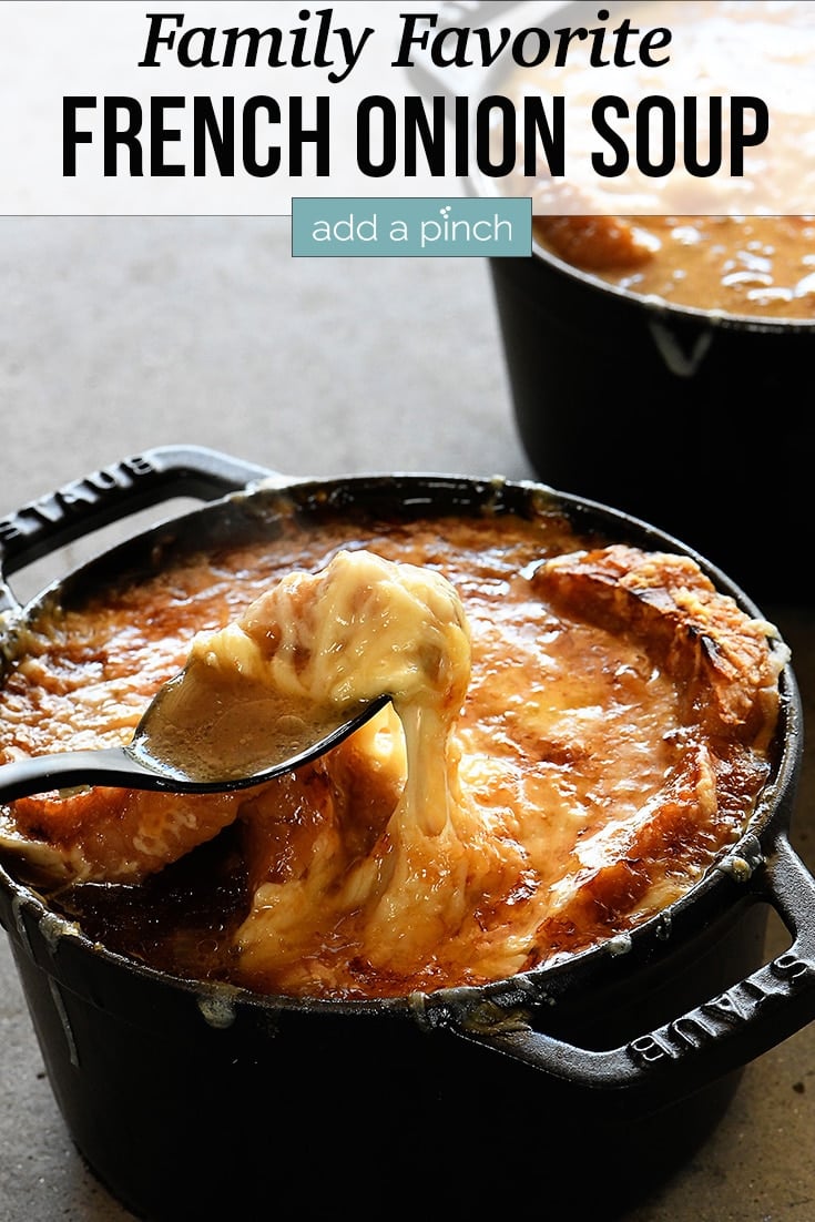 Crock with cheesy French Onion Soup being lifted with spoon - with text - addapinch.com