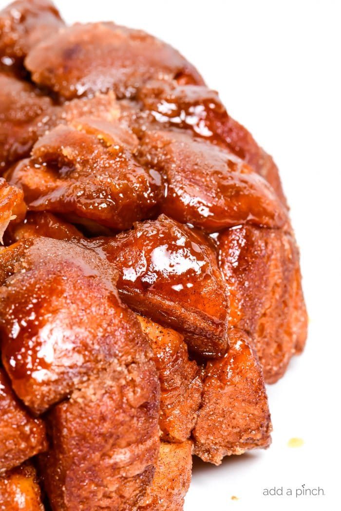 photograph of golden brown monkey bread with a caramel glazed on a white platter.