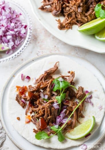 Barbacoa on soft tortilla with lime, cilantro and red onion.