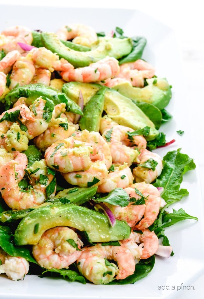Close up photograph of citrus shrimp avocado salad on a white platter. 