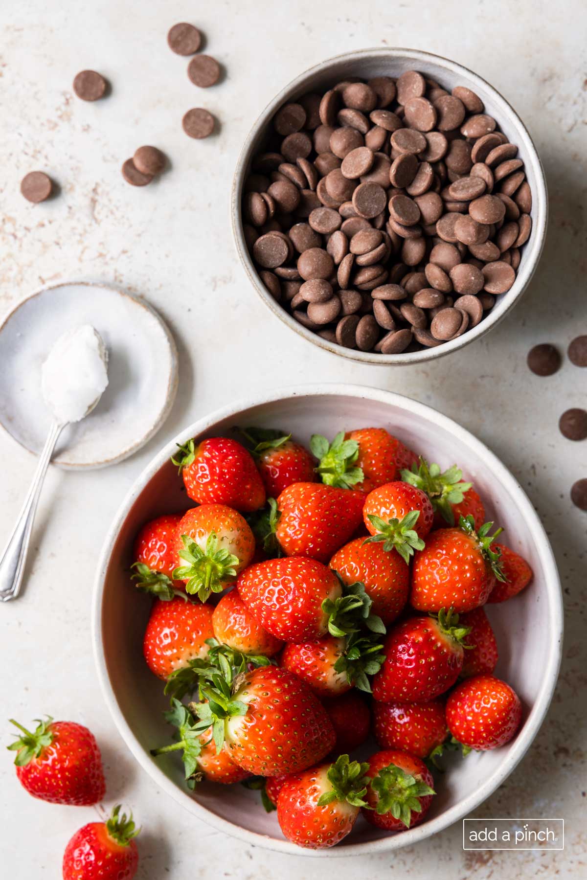 Ingredients to make chocolate covered strawberries: chocolate chips , coconut oil, and ripe strawberries in a bowl. 