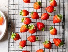Clean strawberries drying on a wire rack.