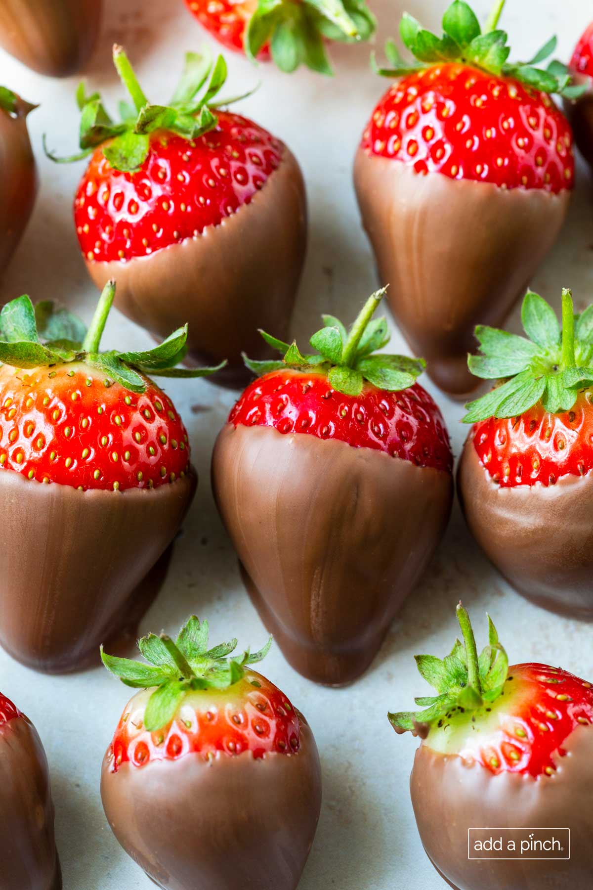Platter filled with rows of fresh strawberries covered in chocolate.