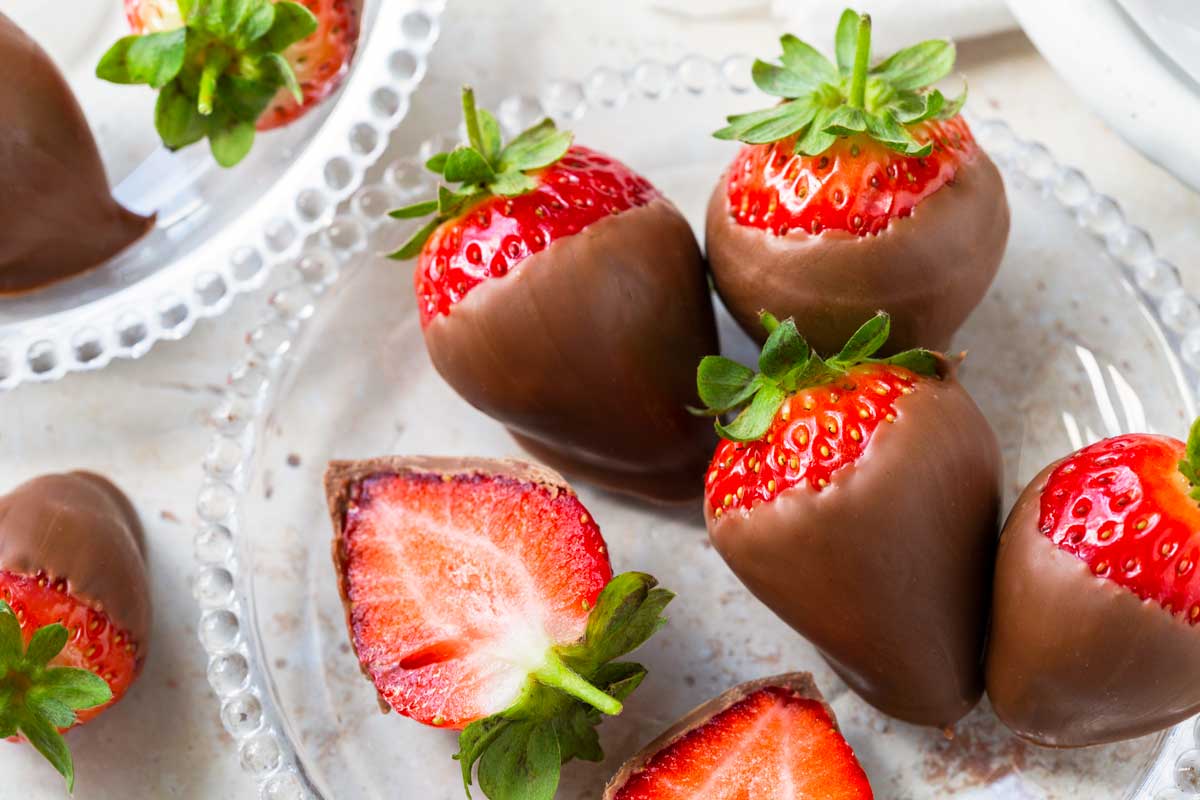 Strawberries dipped in chocolate on a glass plate.