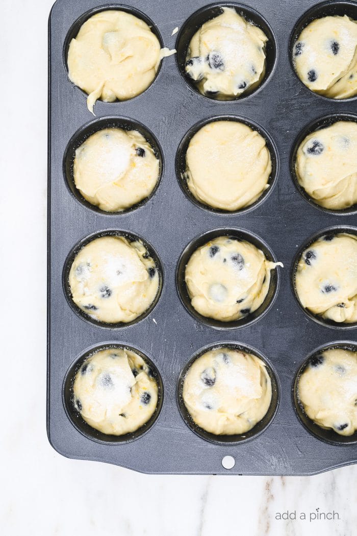 Blueberry muffin batter in muffin pan on a marble counter