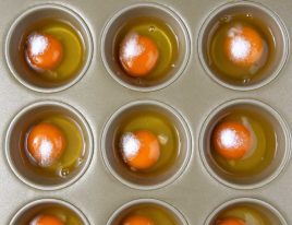 Photo of eggs in a muffin pan with salt added to each egg.