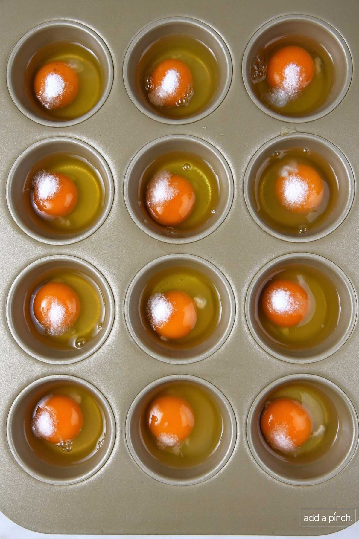 Photo of eggs in a muffin pan with salt added to each egg. 