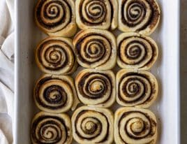 Photo of cinnamon roll slices in a white baking dish.