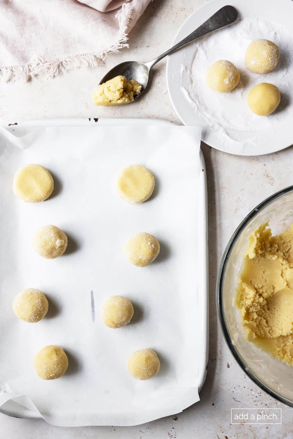 Image of chewy sugar cookie dough being scooped onto a baking sheet.