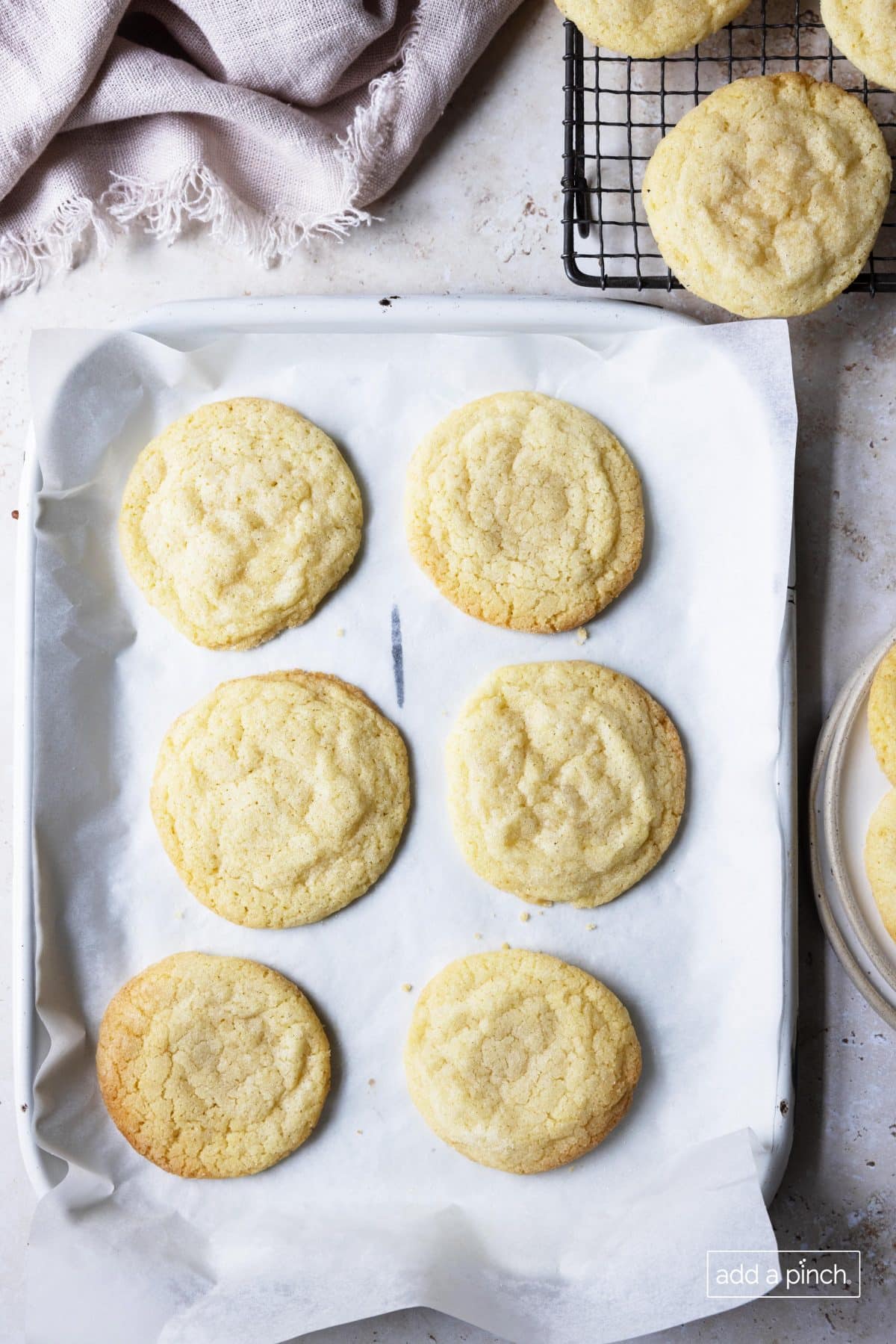 Baked chewy sugar cookies on a parchment paper lined baking sheet.