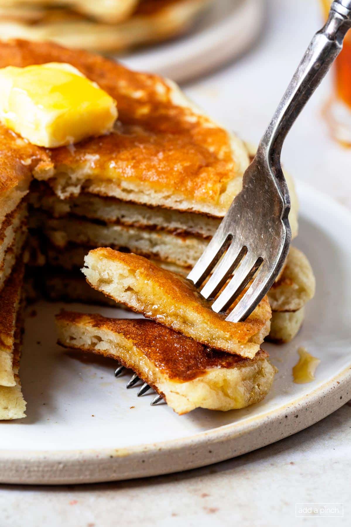Stack of buttermilk pancakes with a bite on a fork.