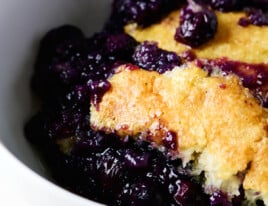 Photo of blueberry cobbler in a white bowl.