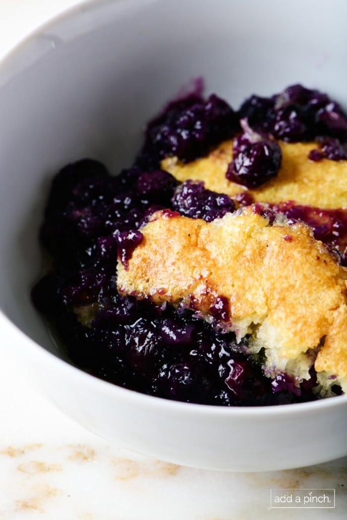 Photo of blueberry cobbler in a white bowl.