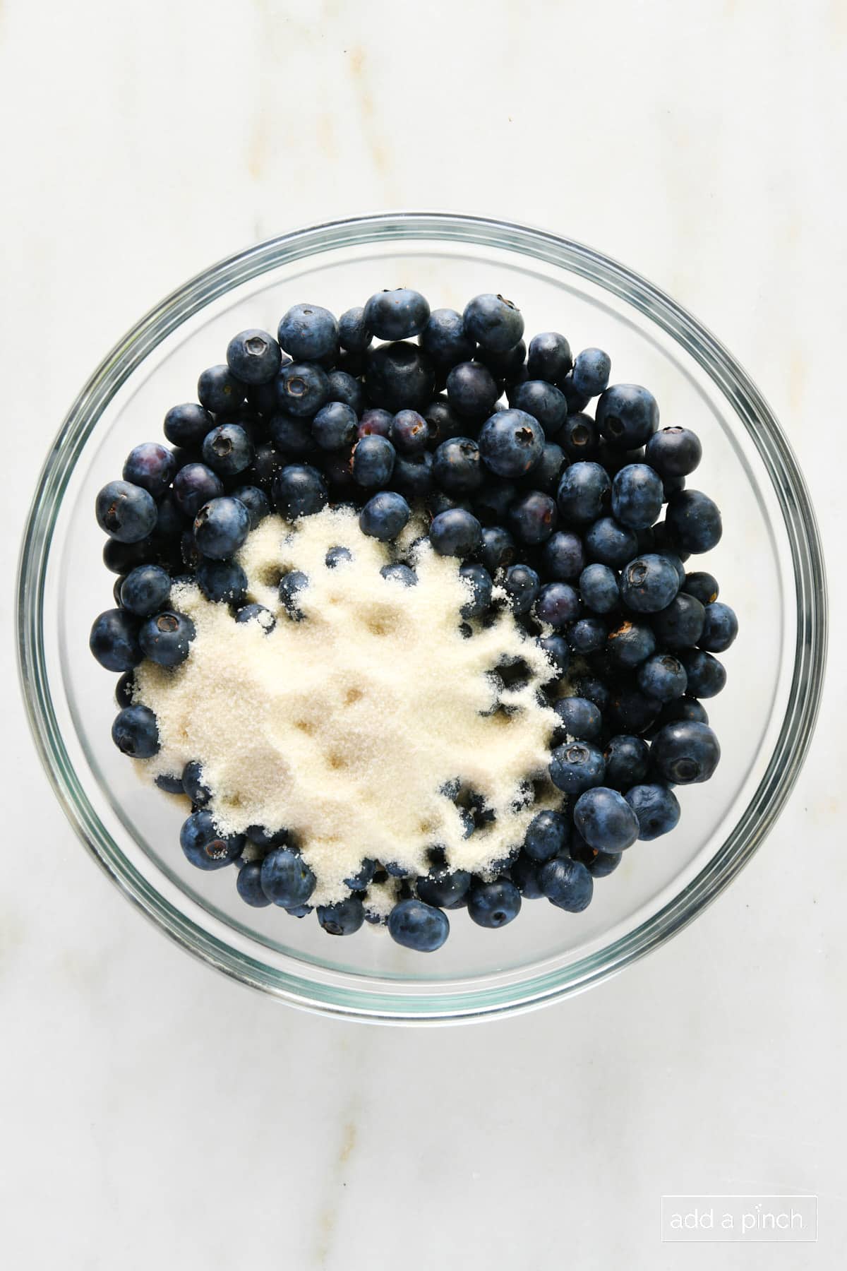 Blueberries and sugar in a glass bowl