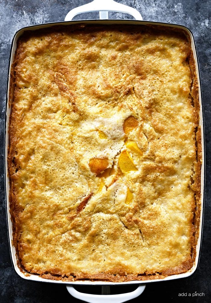 Overhead shot of golden brown and bubbly Easy Peach Cobbler in a white baking dish // addapinch.com