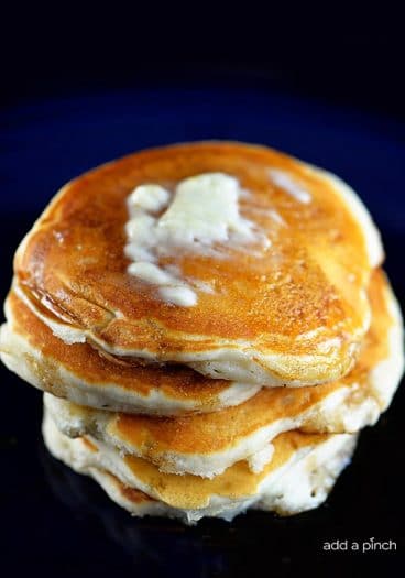 Photograph of buttermilk pancakes topped with butter and maple syrup. // addapinch.com