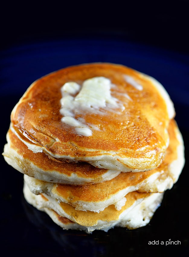 Photograph of buttermilk pancakes topped with butter and maple syrup. // addapinch.com