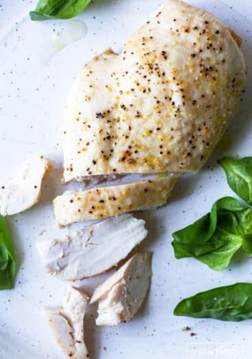 Photo of baked chicken breast on a white plate.