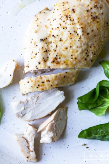Photo of baked chicken breast on a white plate.