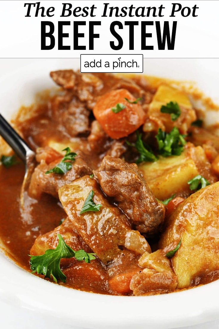 White bowl of beef stew with chunks of beef, carrots, potatoes and other vegetables - with text - addapinch.com