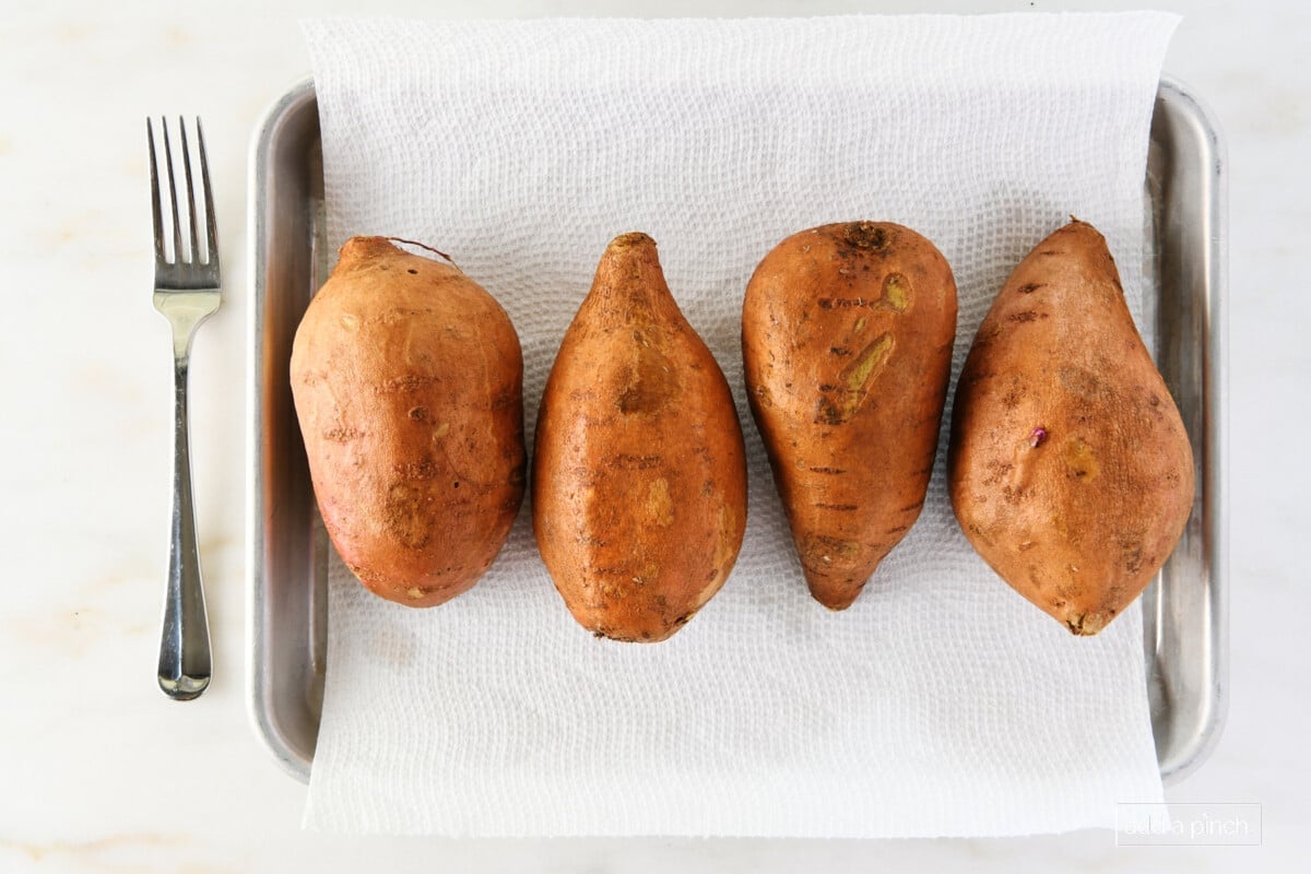 Sweet potatoes on a baking sheet with paper towels.