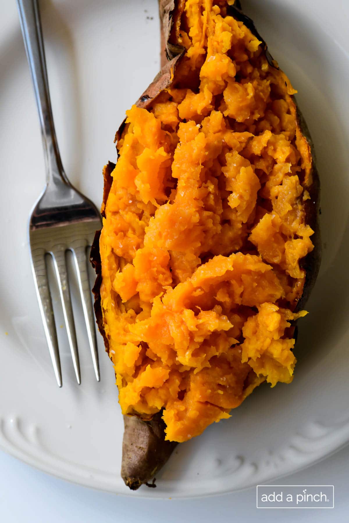 Overhead photograph of baked sweet potato on a white plate.