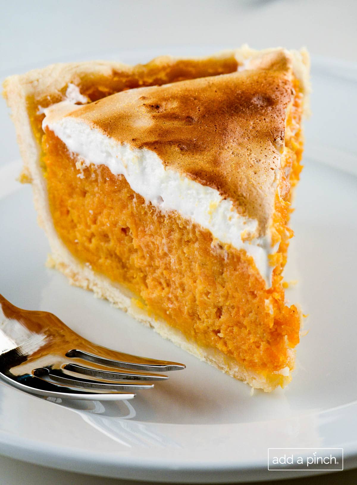 Photograph of slice of sweet potato pie with toasted marshmallow fluff topping. 