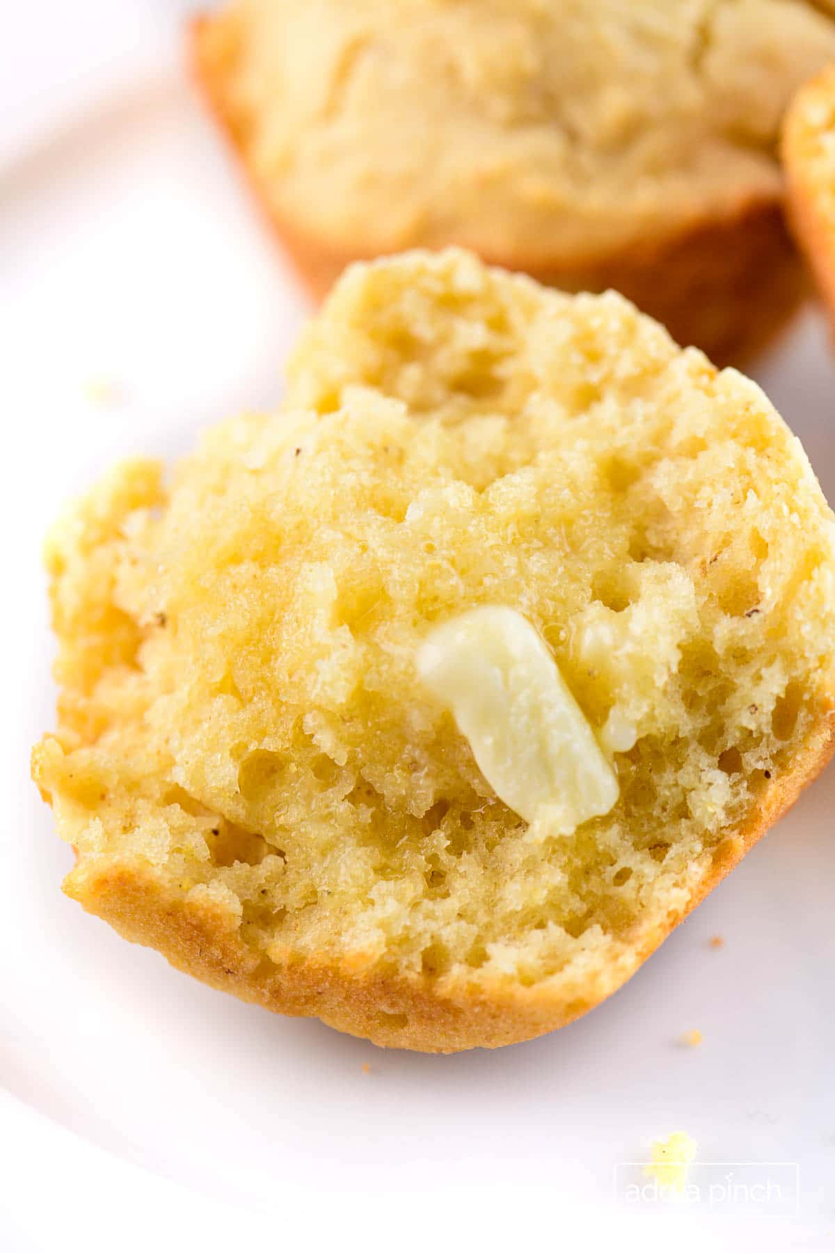 Photograph of cornbread muffin with a pat of butter.