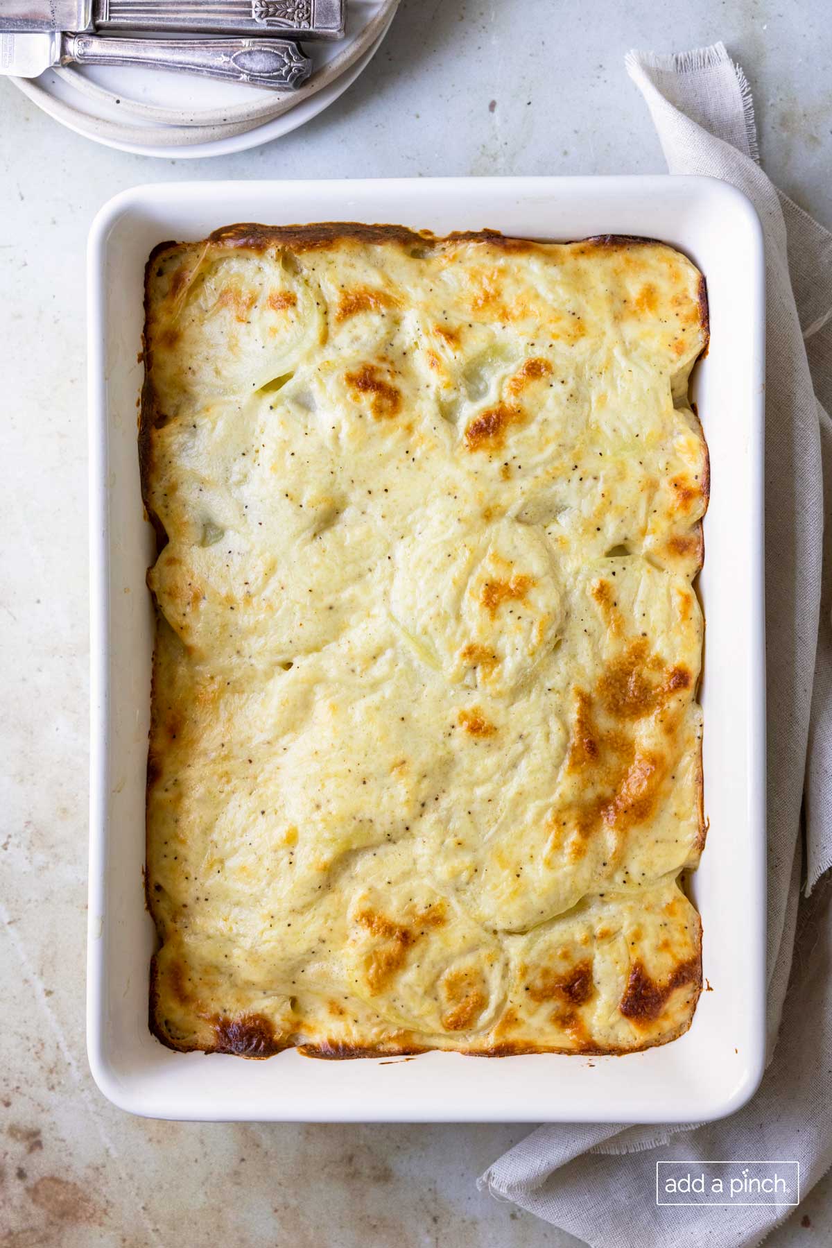 Photo of baked scalloped potatoes in a white baking dish.