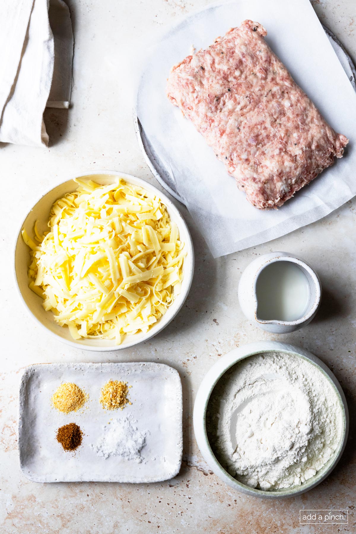 Ingredients for sausage balls: sausage, milk, flour, seasonings and cheese.