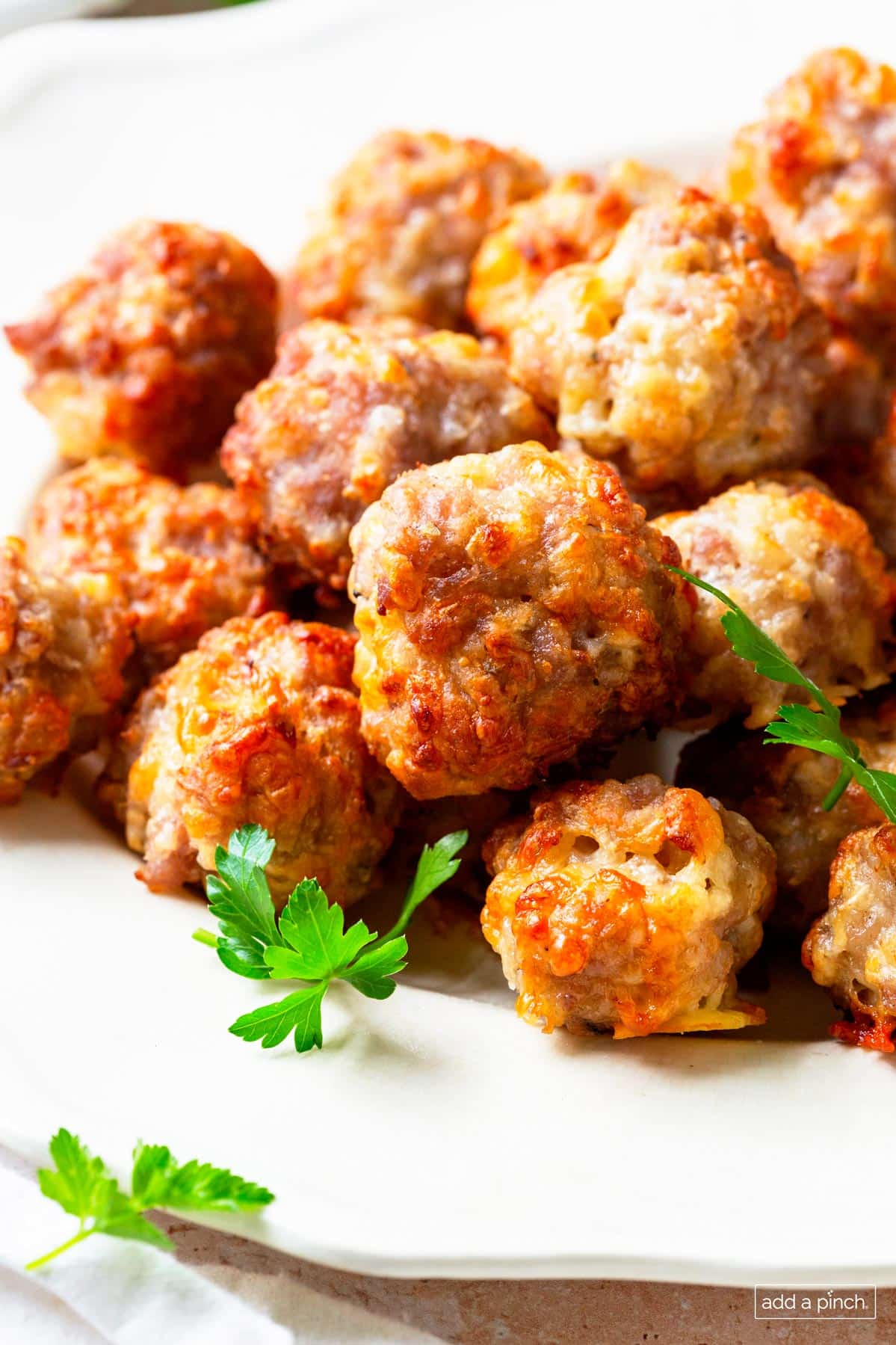Photo of cooked sausage balls on a white serving plate.