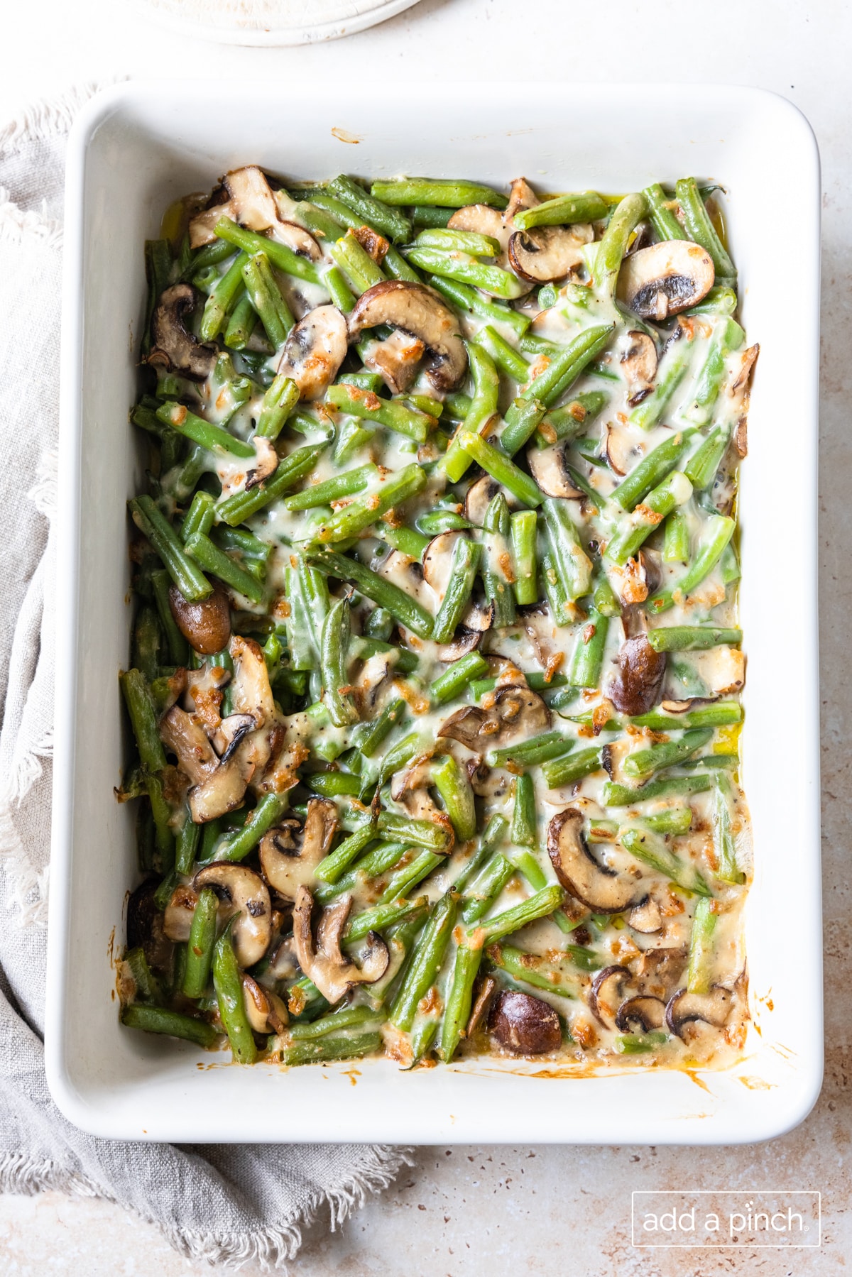 Fresh green bean casserole in a white baking dish ready to be baked.