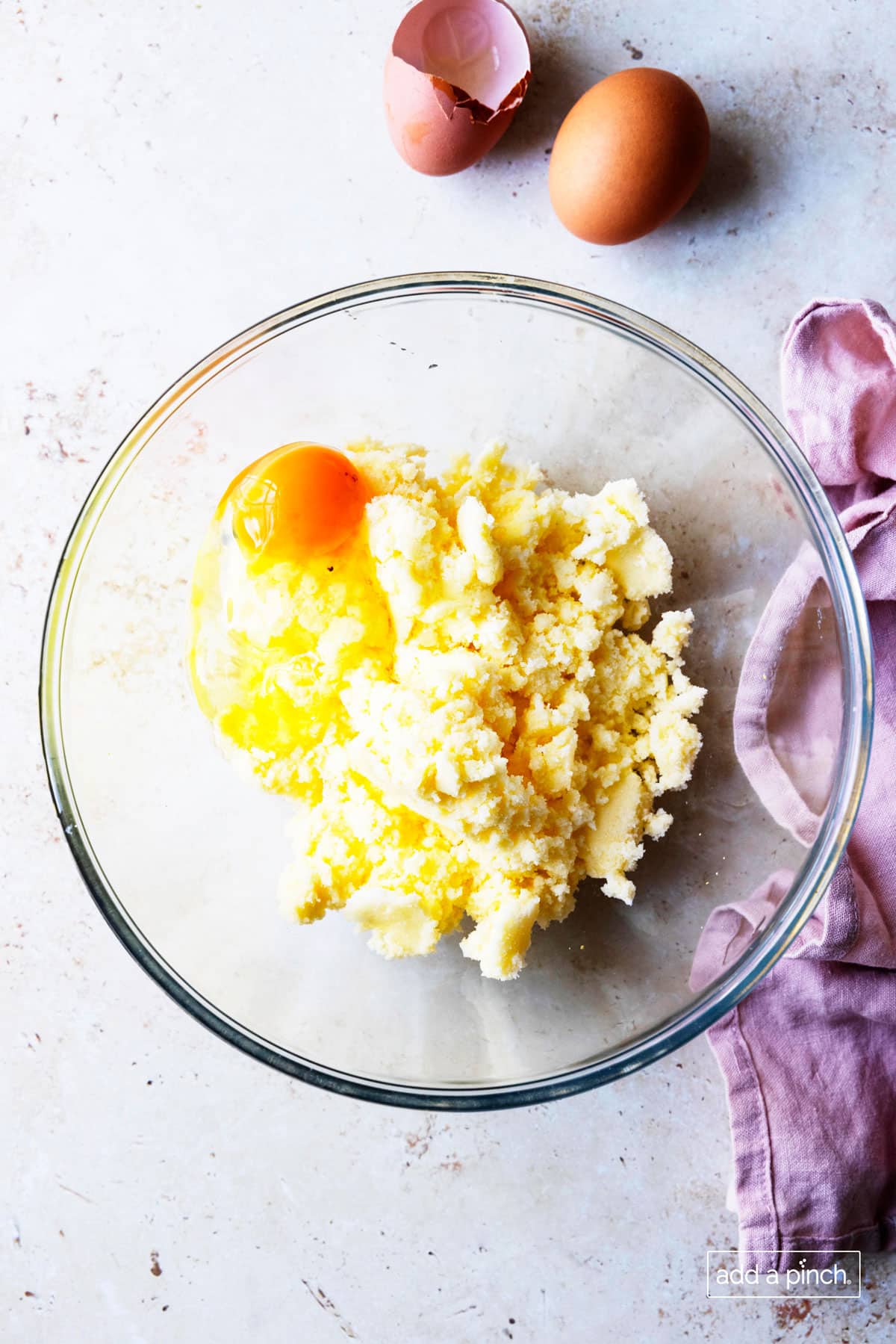 Photo of eggs added to creamed shortening and sugar in a glass bowl.