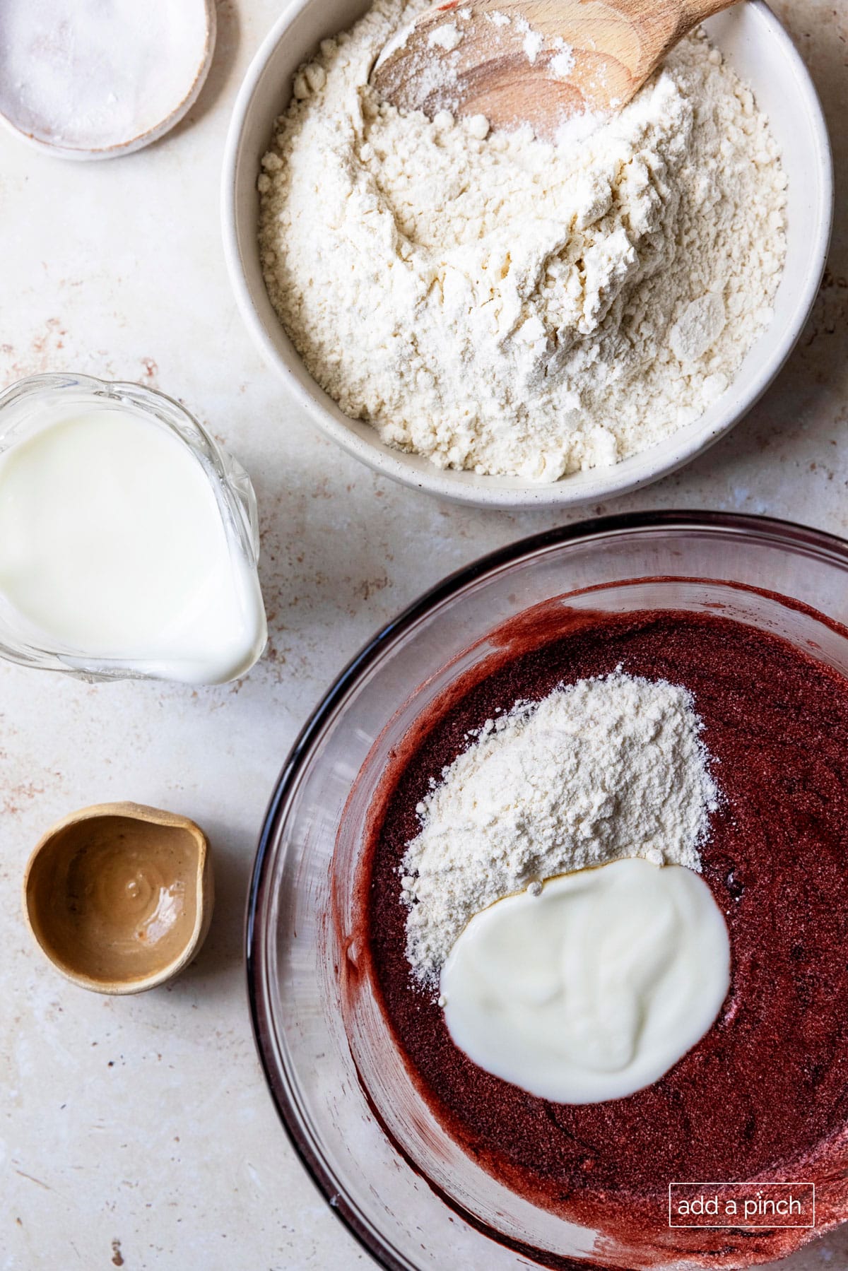 Image of flour and buttermilk being added to red velvet cake batter.