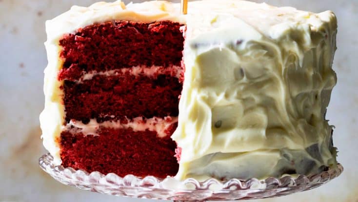 Image of red velvet cake with a lit gold candle.