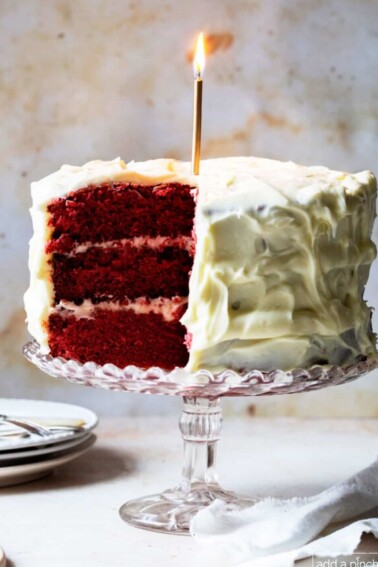 Image of red velvet cake with a lit gold candle.