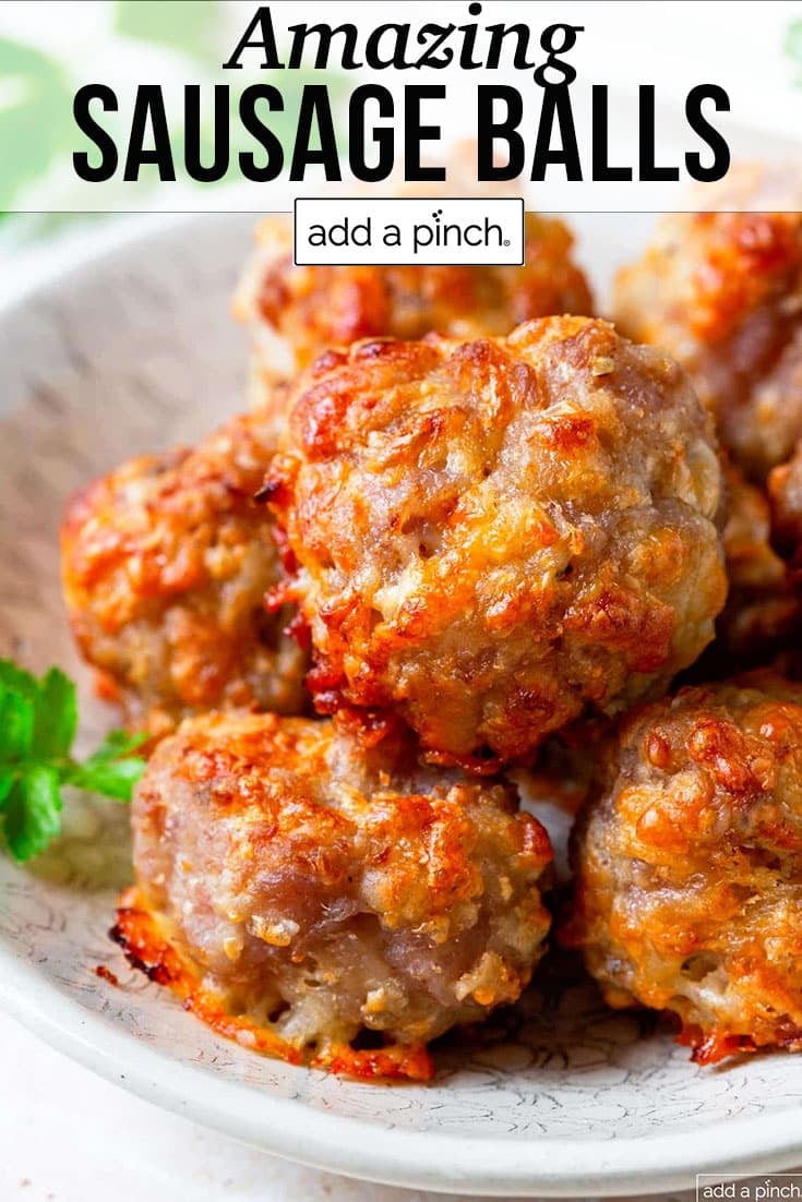 Cheesy, crispy browned sausage balls on a platter with green herbs - with text - addapinch.com